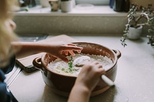 Girl's hand dropping minced leaves into a terracotta dish
