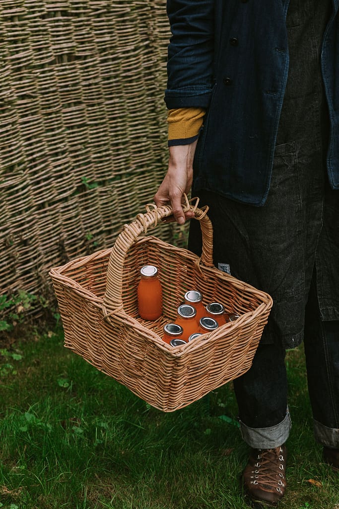 Fresh cold pressed juices in a basket held by a woman