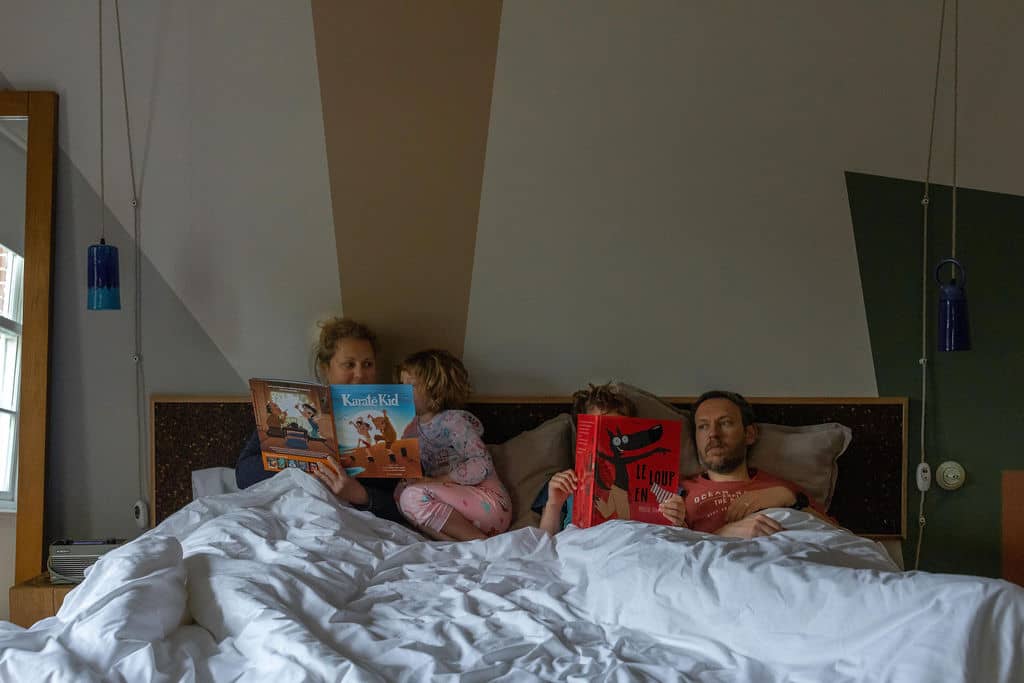 Family of 4 in a bed reading books