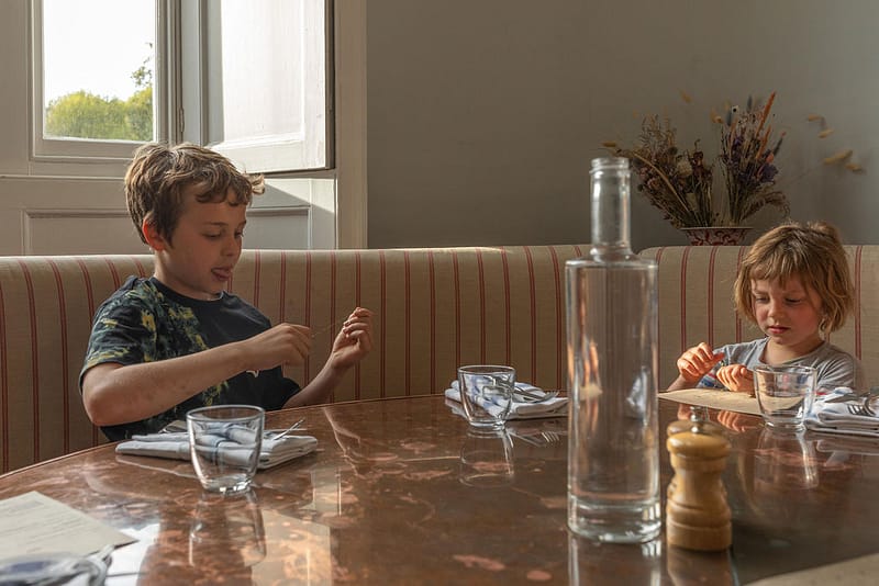 Children at restaurant table with bottle in the middle