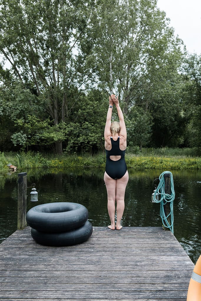 Woman about to dive into natural pool, Cambridgeshire