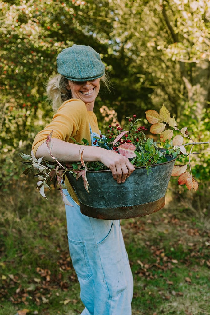 woman holding tin basket full of seasonal foliage